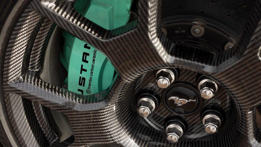 Close-up of a carbon fiber wheel with a Brembo brake caliper and Mustang emblem.