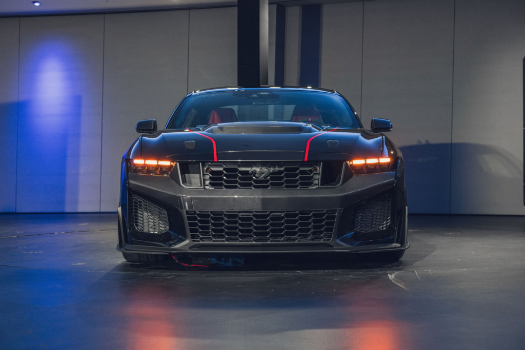 Front view of a sleek black sports car with red accents, in a modern showroom setting.