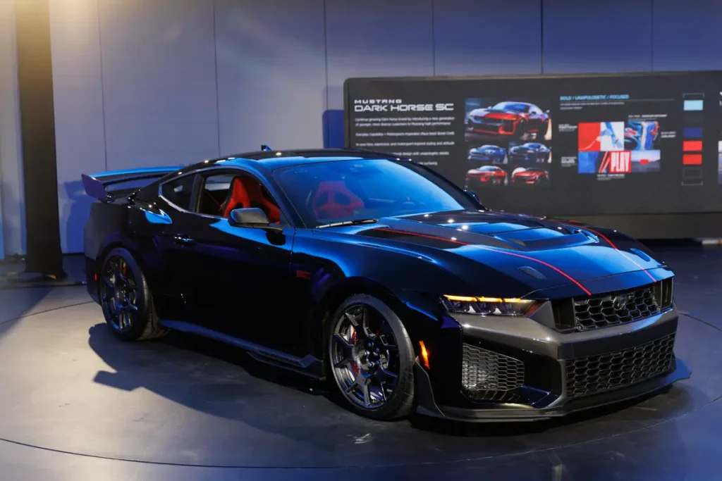 Sleek black sports car with a red interior on display, featuring a spoiler and modern headlights.