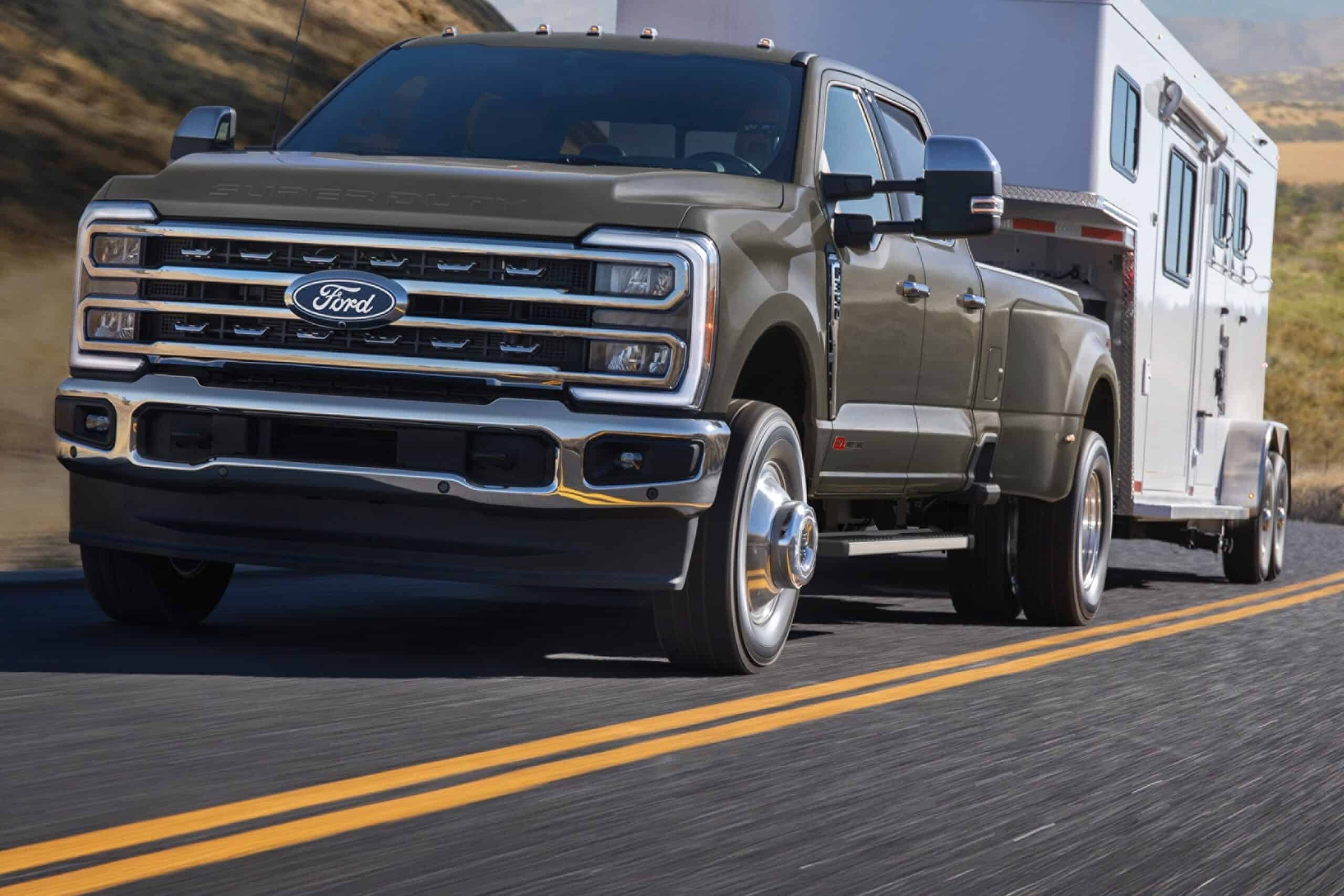 2027 Ford F-250 front three-quarter view towing a horse trailer on a highway
